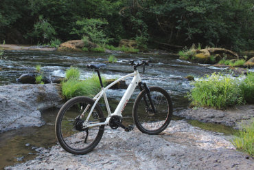 This photo shows the Vvolt Sirius ebike outside near a stream.