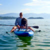 This outdoor gift guide photo shows the author outside on a lake on a paddle board with a dog on a summer day.