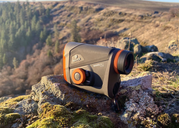 This review photo shows the Maven RF.1 Rangefinder perched on a rock near a cliff in forest.