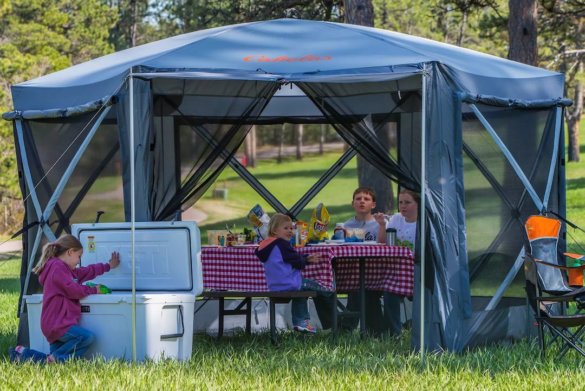 This photo shows the Cabela's Quick-Set Screen Shelter being used by a family during an outdoor picnic.