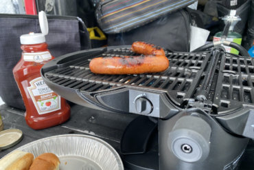 This review photo shows the nomadiQ Grill in use on the tailgate of a pickup during the testing process.