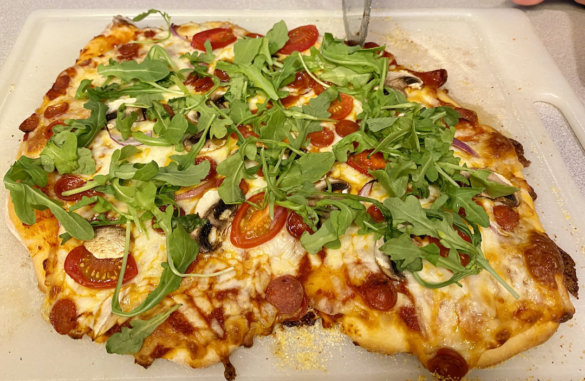 This photo shows a homemade pizza with arugula on top.