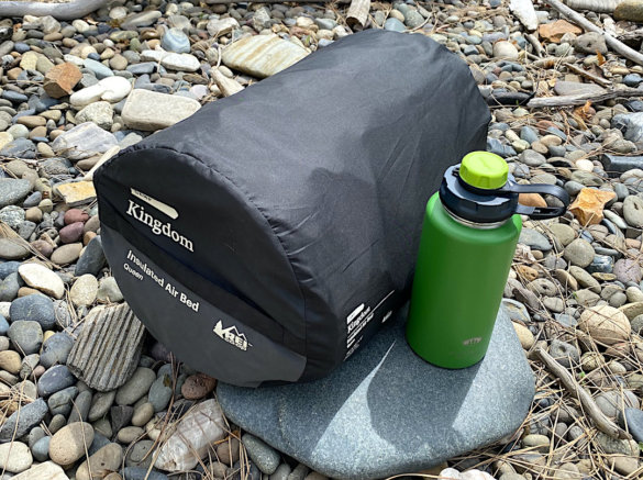 This photo shows the packed size of the REI Co-op Kingdom Insulated Air Bed relative to a standard water bottle.