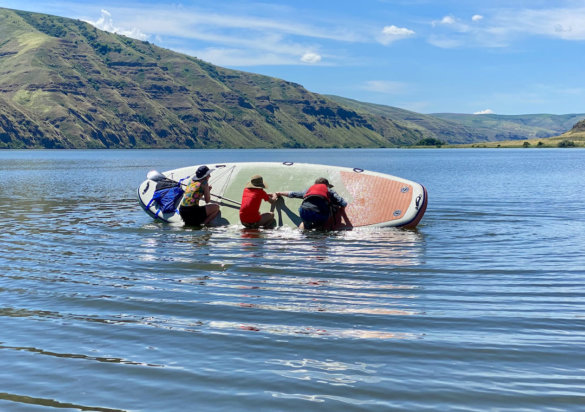 This photo shows three paddlers trying to tip over the ISLE Megalodon 2.0 standup paddle board in the water.