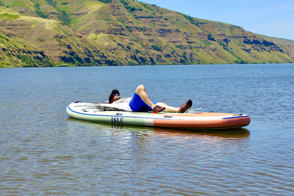 This photo shows the author laying down on the ISLE Megalodon 2.0 15' paddle board while floating on a lake.