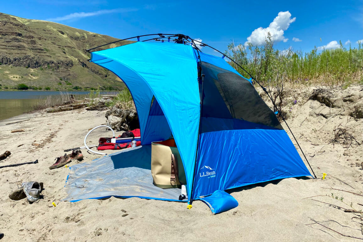 This photo shows the L.L.Bean Sunbuster Folding Shelter pop-up sun shade on a sandy beach during the testing and review process.