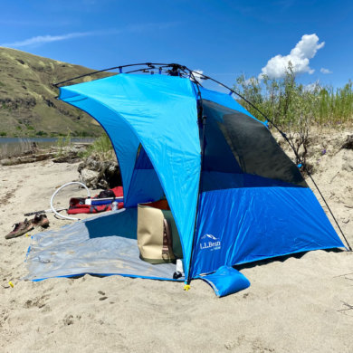 This photo shows the L.L.Bean Sunbuster Folding Shelter pop-up sun shade on a sandy beach during the testing and review process.