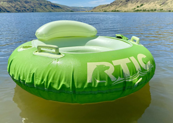 This photo shows the RTIC Tough River Tube in the Tree Frog green color option inflated floating on the water.