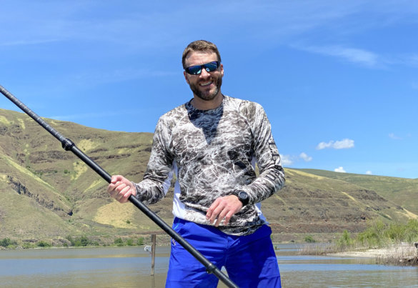 This photo shows Chris Maxcer wearing the L.L.Bean Tropicwear Knit Crew Shirt while on a SUP at a beach during the review and testing process.