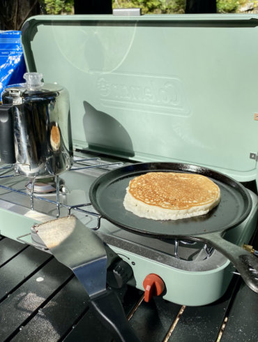 This photo shows the Coleman Cascade 222 two-Burner Camping Stove with a coffee pot and pancake during the testing and review process.