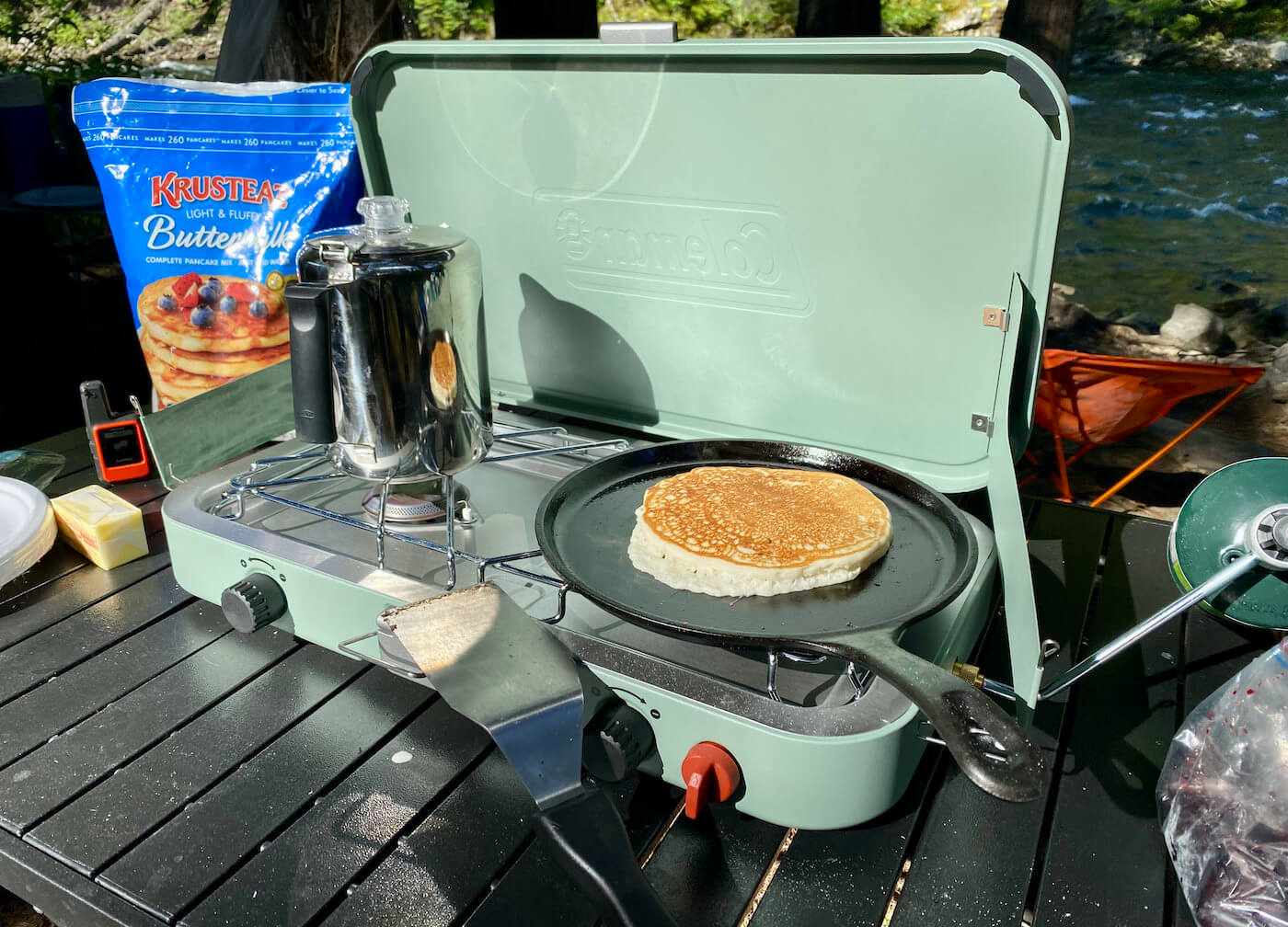 This photo shows the Coleman Cascade 222 two-Burner Camping Stove with a coffee pot and pancake during the testing and review process.