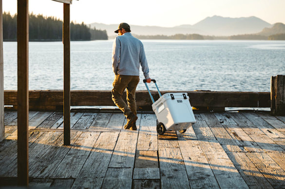 This photo shows a man pulling a YETI Roadie 60 on a dock.