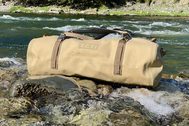 This photo shows the YETI Panga 100L Waterproof Duffel bag near a river.