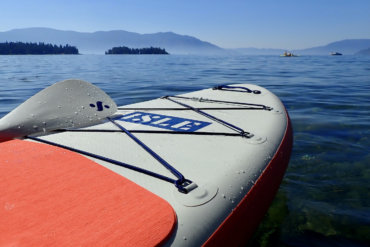 This review photo shows the ISLE Pioneer 2.0 Inflatable Paddle Board floating on a lake.
