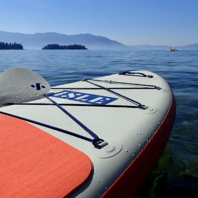 This review photo shows the ISLE Pioneer 2.0 Inflatable Paddle Board floating on a lake.