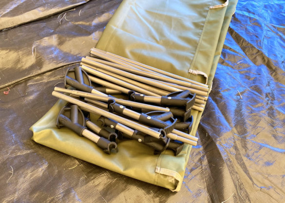 This photo shows the Kijaro Native Ultralight Cot unassembled on a camping tent floor.