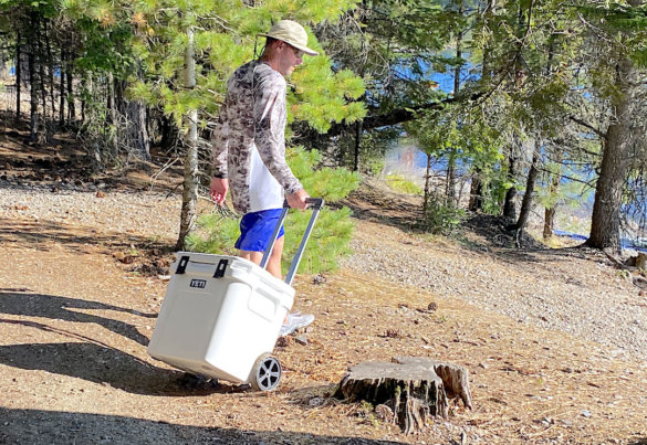 This photo shows the author pulling the YETI Roadie 48 wheeled cooler near a lake during the testing and review process.