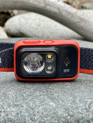 This review photo shows the Black Diamond Spot 400 Headlamp from the front view on a rock.