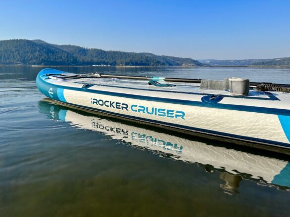 This photo shows a profile view of the iRocker Cruiser Ultra inflatable stand-up paddleboard while it floats on a lake.