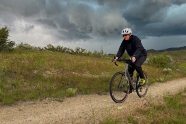 This photo shows the author riding in stormy weather while testing the Showers Pass Timberline Rain Jacket and Rain Pants during the review process.