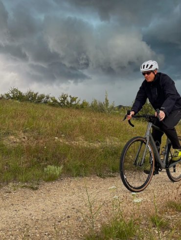 This photo shows the author riding in stormy weather while testing the Showers Pass Timberline Rain Jacket and Rain Pants during the review process.
