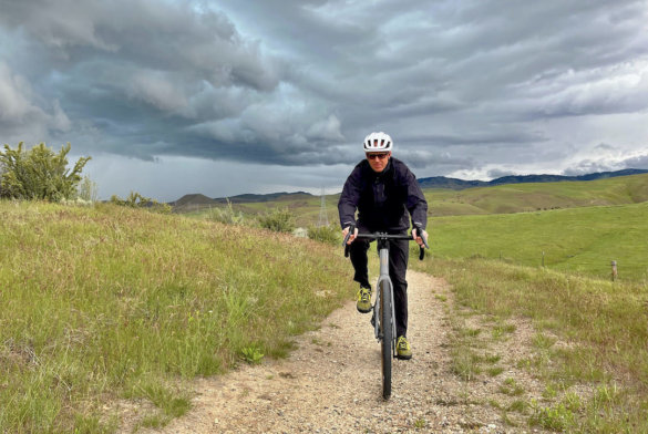 This photo shows the author wearing the Showers Pass Timberline Rain Jacket and Rain Paints while on a gravel bike ride in rainy weather.