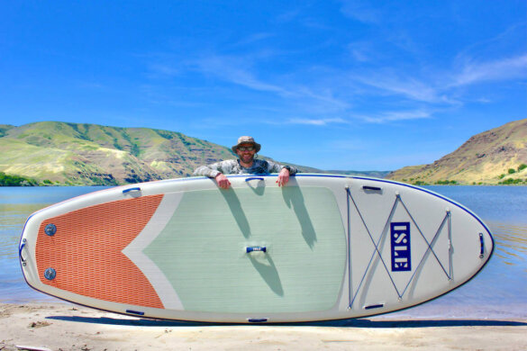 This photo shows the author standing behind the ISLE Megalodon 2.0 inflatable standup paddle board.