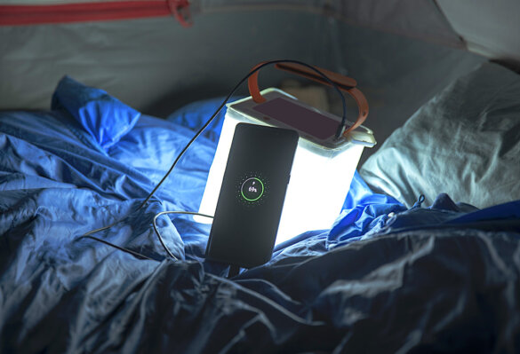 This photo shows the LuminAID PackLite Titan 2-in-1 Power Lantern inside a tent as it charges a smartphone.