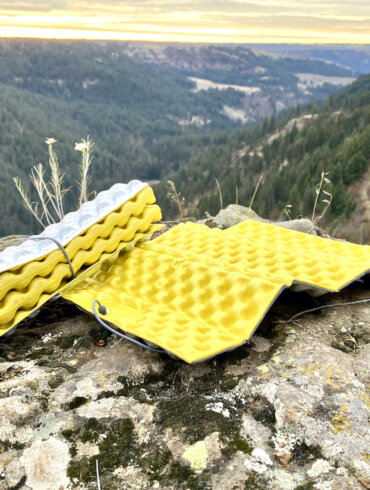 This photo shows two Therm-a-Rest Z Seat foam pads on a rock near a cliff during the testing and review process.