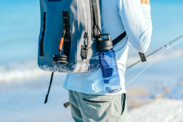 This photos shows a fly fisherman with a YETI Panga Backpack with the new YETI Yonder water bottle attached.