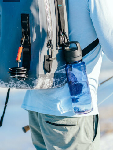 This photos shows a fly fisherman with a YETI Panga Backpack with the new YETI Yonder water bottle attached.