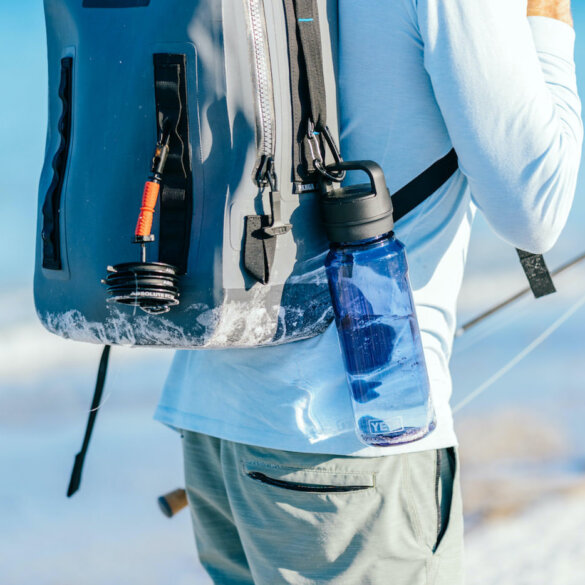 This photos shows a fly fisherman with a YETI Panga Backpack with the new YETI Yonder water bottle attached.