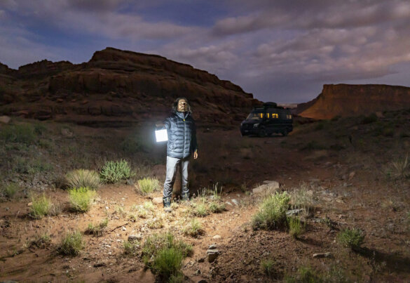 This photo shows a man holding a LuminAid PackLite Titan 2-in-1 Solar Lantern Charger in the dark in a desert.