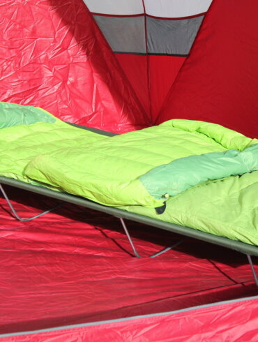 This photo shows the ALPS Mountaineering Lightweight Cot set up inside of a camping tent with a sleeping bag.
