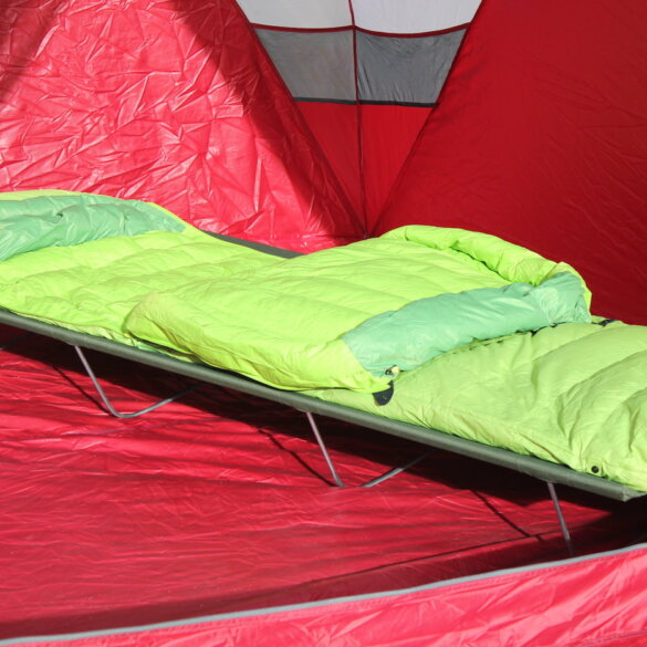 This photo shows the ALPS Mountaineering Lightweight Cot set up inside of a camping tent with a sleeping bag.