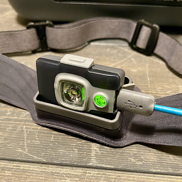 This photo shows the BioLite HeadLamp 325 being charged with a connected usb cord.