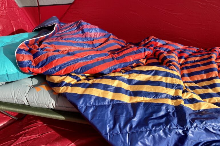This testing and review photo shows the Rumpl Original Puffy Blanket inside a camping tent on an air mattress and camp cot.