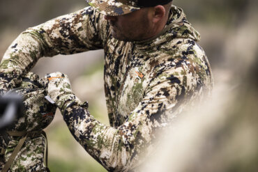 This photo shows a hunter wearing Sitka's new Core Merino 120 Hoody while organizing gear in a Sitka hunting backpack.