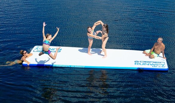 This photo shows kids playing on the O'Brien Runway Inflatable Float on a lake.