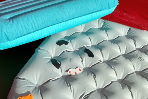 This photo shows the Sea to Summit Pillow Lock pillow attachment system on an inflatable sleeping air mattress with an Aeros pillow nearby.