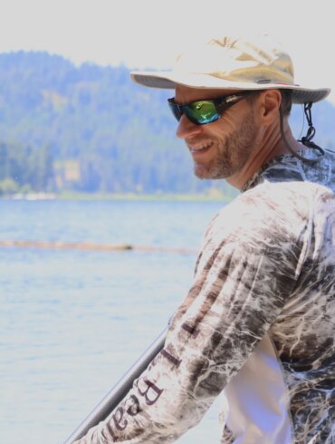 This review photo shows the author wearing the Smith Guide's Choice polarized sunglasses with a lake in the background during the testing process.
