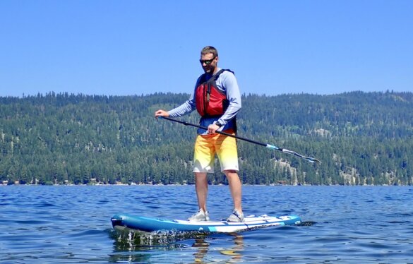 This photo shows the author standup paddleboarding on a lake while wearing the Smith Guide's Choice polarized sunglasses during the testing and review process.