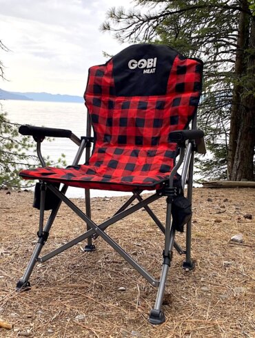 This review photo shows the Gobi Heat Terrain Heated Camping Chair at a camping spot near a lake during the testing process.