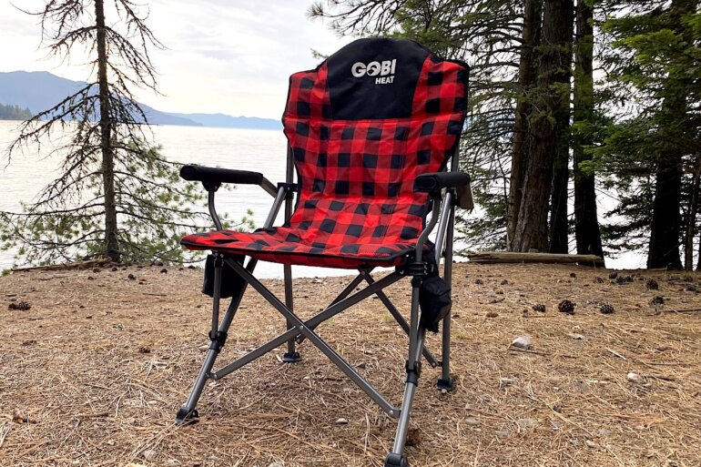 This review photo shows the Gobi Heat Terrain Heated Camping Chair at a camping spot near a lake during the testing process.