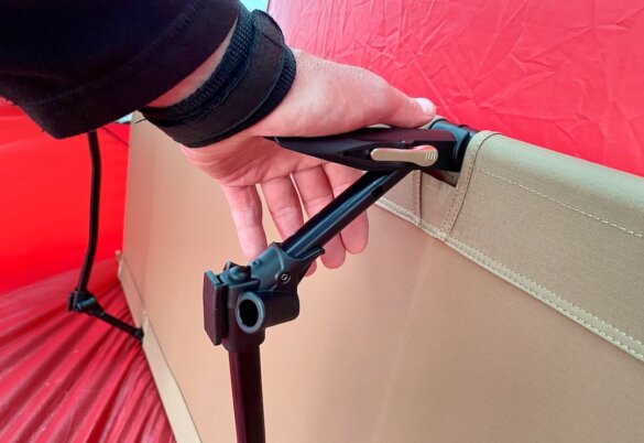 This photo shows the author demonstrating the lever tension system used to setup the Helinox Cot One Convertible camping cot.