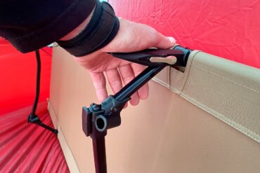 The testing and review photo shows the author using the Helinox Cot One Convertible lever system to set up the cot for camping.