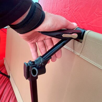 The testing and review photo shows the author using the Helinox Cot One Convertible lever system to set up the cot for camping.