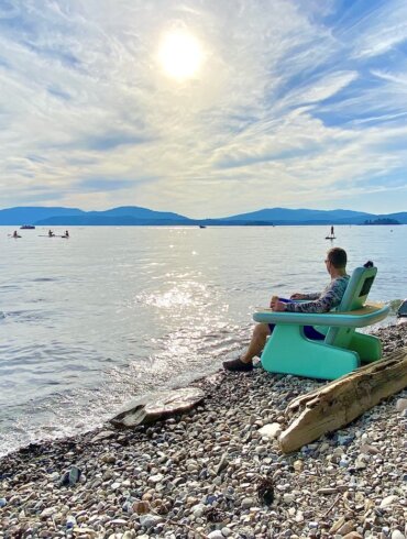 This review photo shows the author testing the BOTE Inflatable AeroRondak Chair on a beach by a lake.