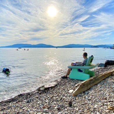 This review photo shows the author testing the BOTE Inflatable AeroRondak Chair on a beach by a lake.