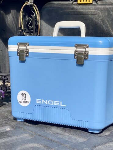 This review photo shows the Engel 19 Quart Drybox/Cooler on the tailgate of a pickup truck out in a forest during the real-world testing process.